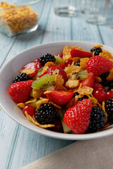 Corn flakes with berry fruits and kiwi, served in a bowl.