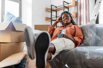 Obraz premium moving, people and real estate concept - happy smiling woman with boxes sitting on sofa with cup of coffee at new home