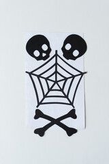 two paper skulls and crossbone with spider wed