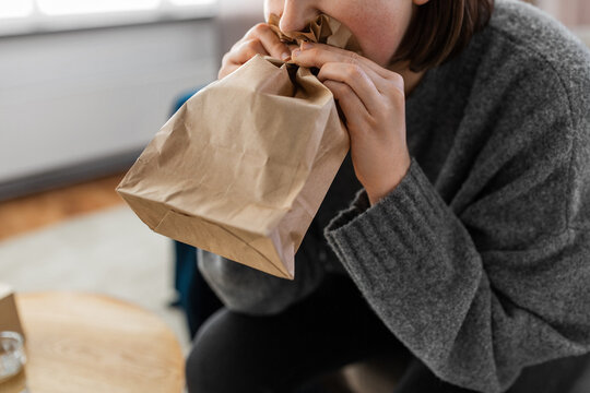 mental health and psychological problem concept - close up of woman having panic attack breathing to bag at home