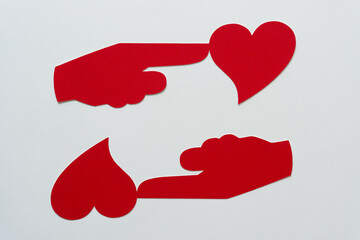 two red paper manicules with fused hearts on blank paper