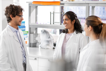 science, work and people concept - international group of happy scientists talking in laboratory