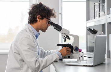 science research, work and people concept - male scientist with microscope working in laboratory