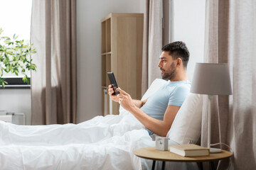 technology, internet and people concept - man with tablet pc computer in bed at home bedroom