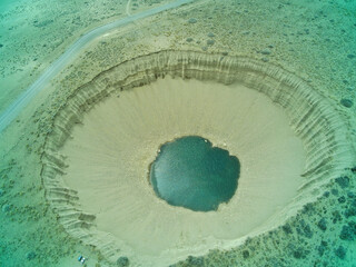 Vista de un pozo gigante natural en la tierra, con agua en el fondo.