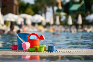 children's toys bucket, watering can on the background of the pool
