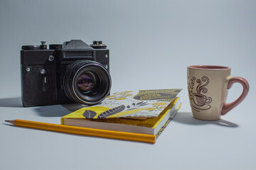 Vintage camera, notepad, pencil and cup pf coffee on table isolated on white background.