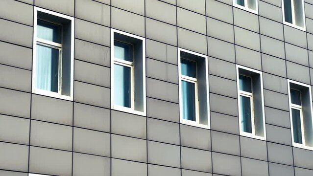Windows of a modern factory office building, covered with metal building cladding. Long shot