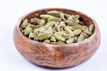 Closeup top view of dried green Elettaria cardamomum fruits with seeds, cardamom spice scattered on white background