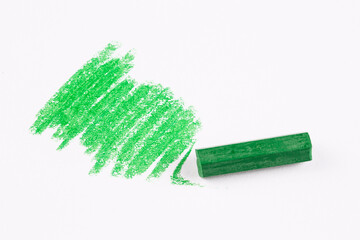Green painted pastel crayons on a white background