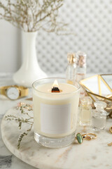 Composition with burning soy candle on white marble table
