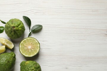 Fresh ripe bergamot fruits with green leaves on white wooden table, flat lay. Space for text - obrazy, fototapety, plakaty