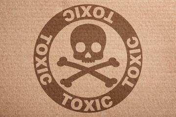 Hazard warning sign (skull-and-crossbones symbol and word TOXIC) on cardboard, top view