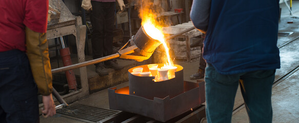 Workers molding objects in the foundry, pouring melted metal in molds