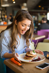 Young woman eating pancakes in the restaurant