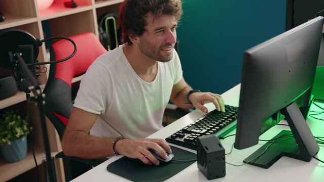 Young hispanic man streamer playing video game using computer at music studio