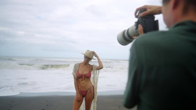 Sliding reveal of model on black sand beach being photographed for content