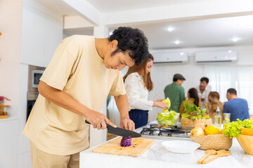 Asian man using knife cutting fresh red cabbage on cutting board in the kitchen at home. Happy female enjoy cooking and having dinner eating healthy food on holiday vacation