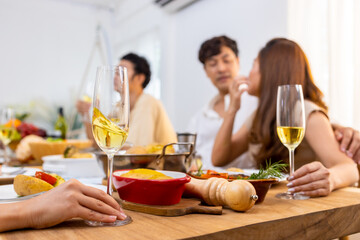 Group of Asian man and woman friends having dinner with drinking wine and talking together on dining table at home. Happy people friendship enjoy reunion meeting celebration party on holiday vacation
