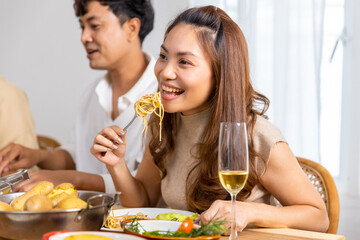 Group of Asian man and woman friends having dinner with drinking wine and talking together on dining table at home. Happy people friendship enjoy reunion meeting celebration party on holiday vacation