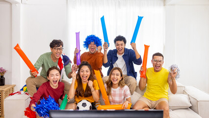 Group of Asian man and woman friends watching soccer games national competition on television with eating snack together at home. Sport fans people shouting and celebrating sport team victory match.