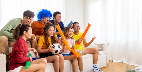 Group of Asian man and woman friends watching soccer games national competition on television with...