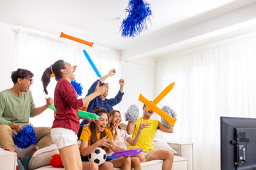 Group of Asian man and woman friends watching soccer games national competition on television with...