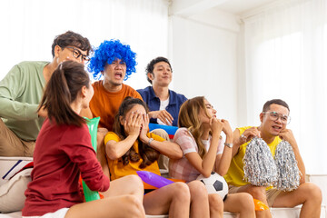 Group of Asian man and woman friends watching soccer games world cup competition on television with...