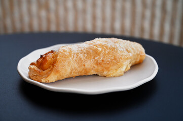 Close up of a quesito (cream cheese-filled pastry twist from Latin America) on a plate | Un quesito (hojaldre latinoamericano relleno de queso crema) en un plato