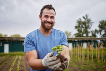 Happy farming worker with a plant on an agriculture farm with a smile. Farmer advertising...