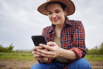 Farmer texting or scrolling on social media on a phone for online sustainability tips relaxing on...