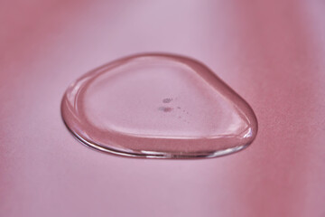 A drop of cosmetics or perfume on a pink background.