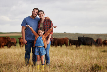 Naklejka na ściany i meble Happy family standing on a farm, cow in background and with a vision for growth in industry portrait. Countryside couple, people or farmer in a field of grass, cattle and free range livestock animals