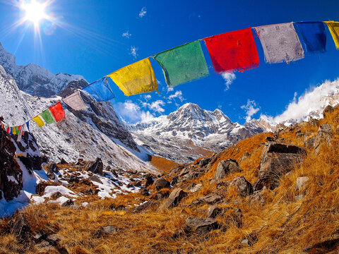 Vibrant prayer flags fluttering in the Himalayan mountains under a bright blue sky and shining sun. Annapurna Basecamp Himalayas, Nepal