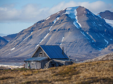 Wooden cabin in arctic tundra under mountain in Svalbard