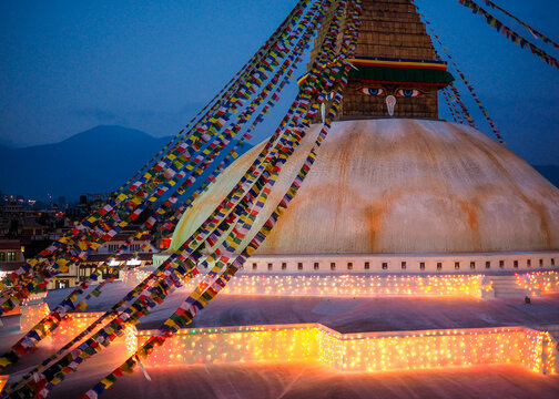 The Illuminated Boudhanath Stupa in Kathmandu Valley at Dusk Decorated with Colorful Buddhist Prayer Flags (Lungta)