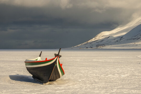 Traditional Colorful Rowing Boat on a Vast, Frozen, Snow-Covered Ice Field in the Remote Arctic Landscape