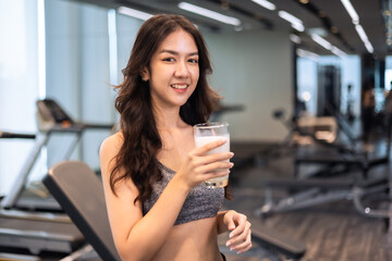 Attractive fitness asian woman finishing workout and drinking protein milk shake vitamins after training. Bodybuilding. Healthy lifestyle. - Powered by Adobe