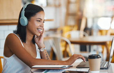 Happy student relaxing, studying or searching online videos on her laptop at a coffee shop with...