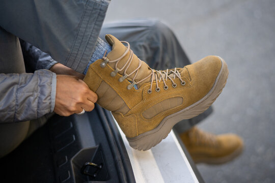 U.S. Army female soldier putting on combat boots and backpack before a hike.