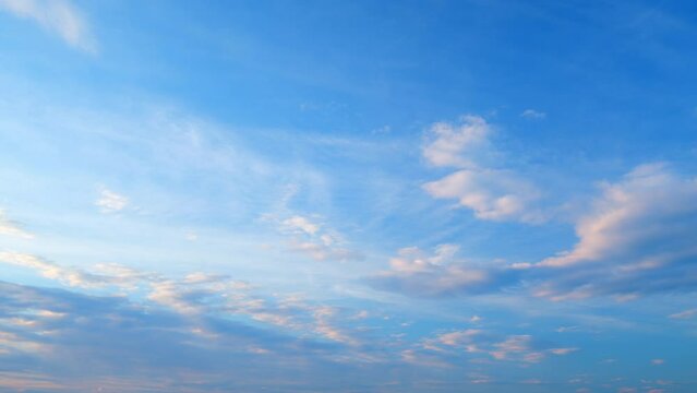 Floating fluffy clouds. Two layers of cloudiness. Blue summer sky with clouds moving in different directions. Time lapse.