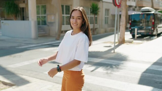 Young beautiful hispanic woman standing with arms crossed gesture at street