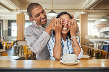 A man covering a happy womans eyes for as a greeting, for a surprise and on a restaurant, cafe or...