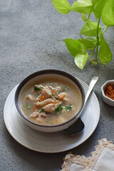 a bowl of chicken soup in grey background