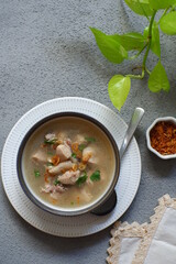 a bowl of chicken soup in grey background