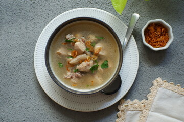 a bowl of chicken soup in grey background