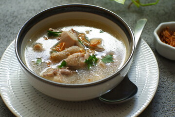 a bowl of chicken soup in grey background