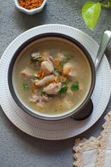 a bowl of chicken soup in grey background