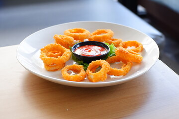 a plate of fried onion rings with tomato sauce 