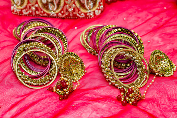 Close up of Hindu bridal bangles and jewelries on red carpet.